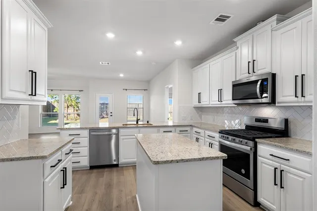a kitchen with granite countertop a sink a counter top space stainless steel appliances and cabinets