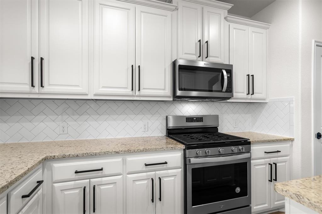 505 Maverick Street Anna, TX 75409 - Photo 26 of 39 a kitchen with granite countertop white cabinets and a stove top oven