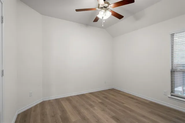 an empty room with wooden floor fan and windows