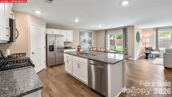 a kitchen with stainless steel appliances granite countertop a refrigerator a stove and a sink