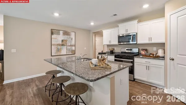 a kitchen with stainless steel appliances granite countertop a sink a stove a microwave a refrigerator and cabinets