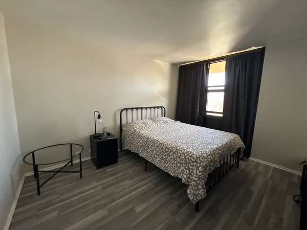 a bed sitting in a bedroom next to a window with a chandelier