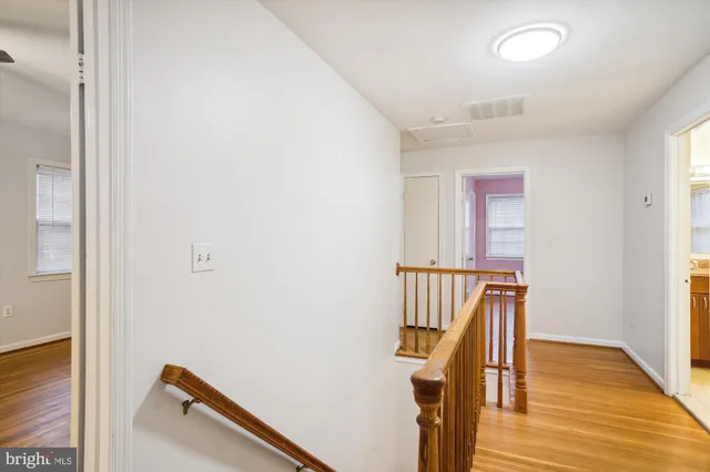 an empty room with wooden floor ceiling fan and windows