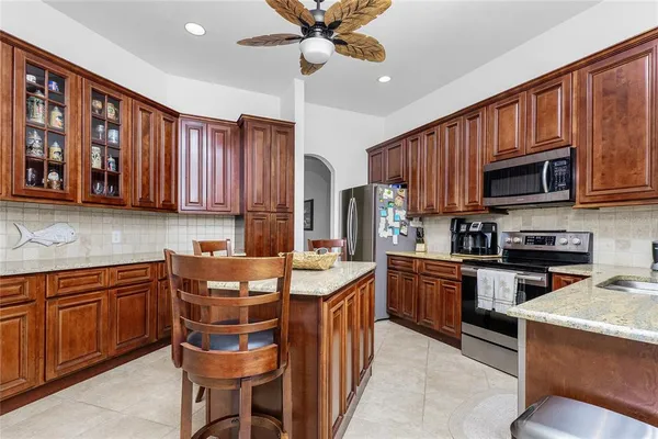a kitchen with granite countertop wooden cabinets a center island and stainless steel appliances