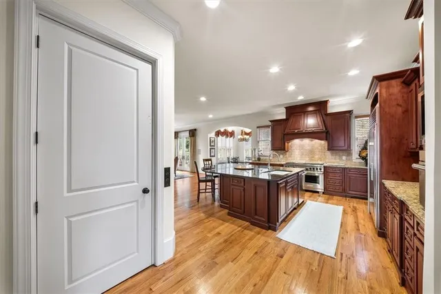 a kitchen with stainless steel appliances kitchen island granite countertop a table chairs and a refrigerator