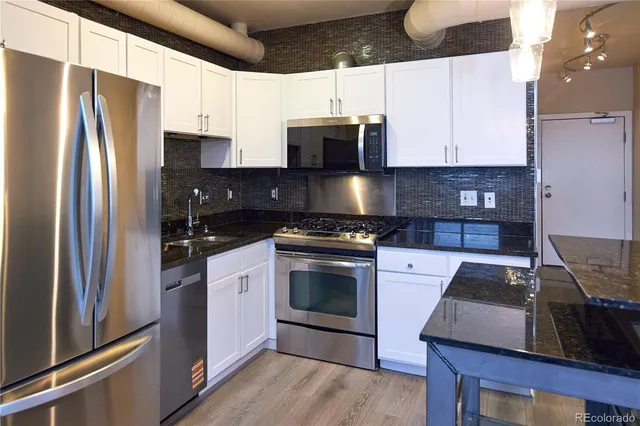 a kitchen with granite countertop a refrigerator stove and microwave