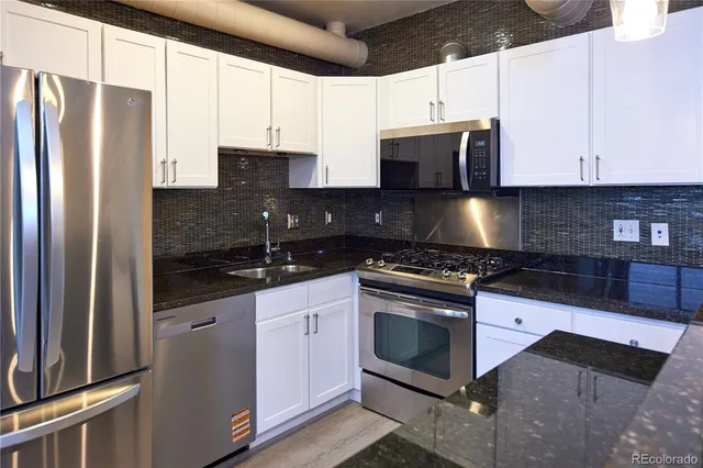 a kitchen with stainless steel appliances granite countertop a stove a refrigerator and a sink