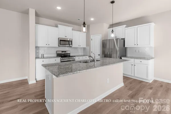 a kitchen with kitchen island a sink a stove a refrigerator and white cabinets