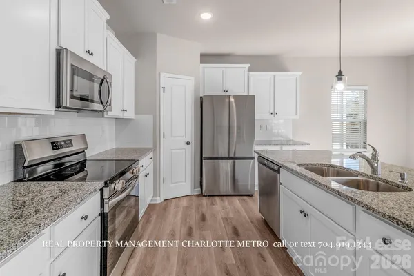a kitchen with stainless steel appliances granite countertop a refrigerator a sink and a stove