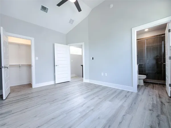 an empty room with wooden floor and a ceiling fan