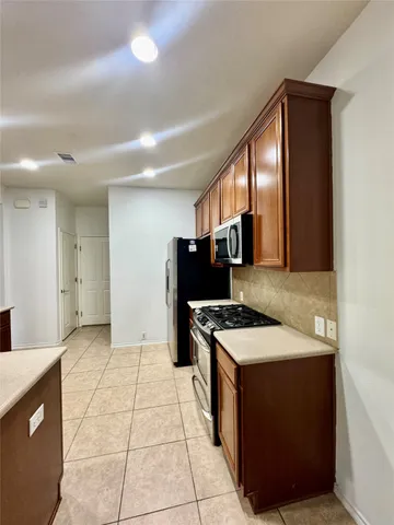 a kitchen with stainless steel appliances a sink a stove a microwave a refrigerator and cabinets