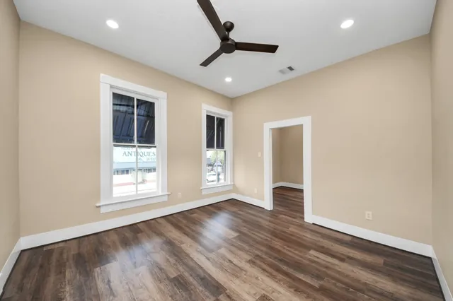 an empty room with wooden floor and windows