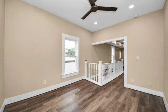 a view of a room with wooden floor fan and windows