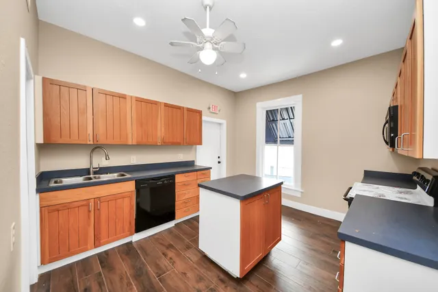 a kitchen with stainless steel appliances granite countertop a stove a sink dishwasher and a refrigerator with wooden floor