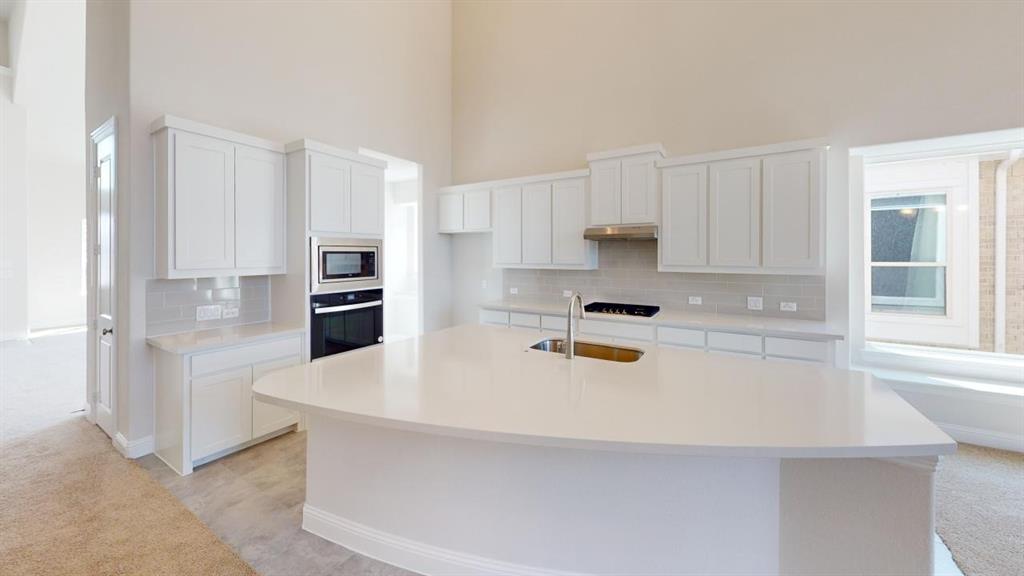 8407 Cornerstone Drive Rowlett, TX 75088 - Photo 24 of 25 Spacious kitchen featuring an oversized island with an undermount sink, white cabinetry, integrated stainless steel appliances, and tile backsplash