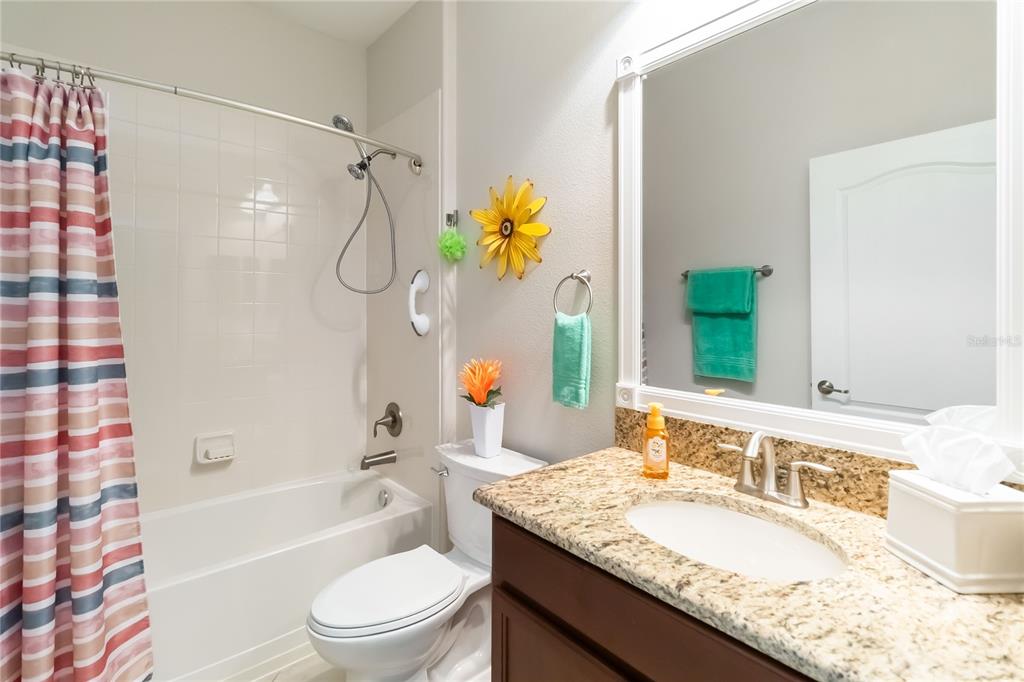 6805 Sundrop Street Harmony, FL 34773 - Photo 20 of 24 a bathroom with a granite countertop sink a toilet and shower