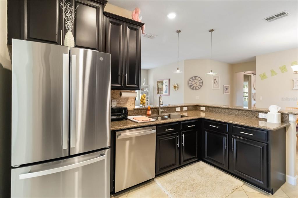 6805 Sundrop Street Harmony, FL 34773 - Photo 9 of 24 a kitchen with stainless steel appliances granite countertop a refrigerator a sink a stove with wooden floor