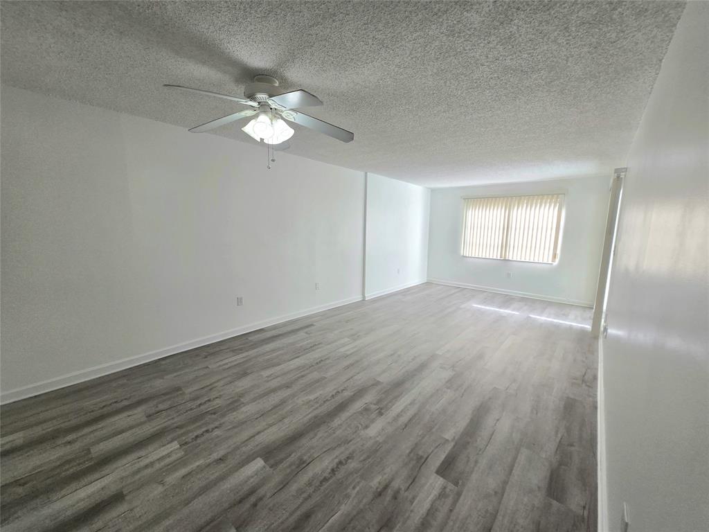 6503 Winfield Boulevard, Unit 107D Margate, FL 33063 - Photo 7 of 24 an empty room with wooden floor fan and windows