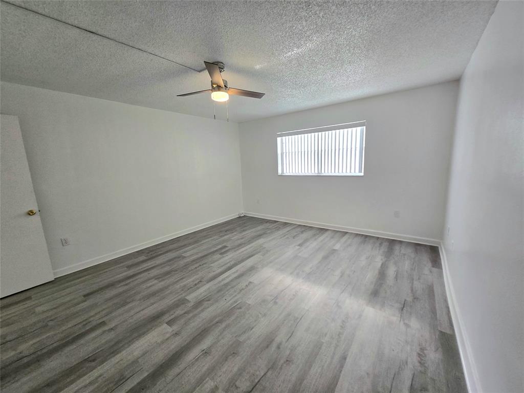 6503 Winfield Boulevard, Unit 107D Margate, FL 33063 - Photo 9 of 24 wooden floor in an empty room with a window