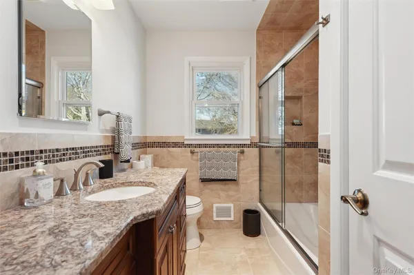 a bathroom with a granite countertop sink a mirror and a shower