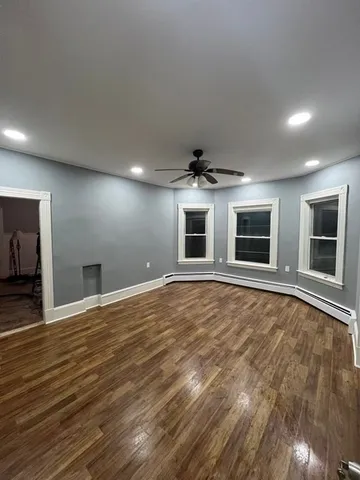 a view of an empty room with window and wooden floor