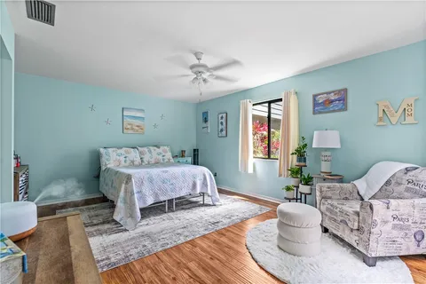 a spacious bedroom with a bed a chandelier and mirror