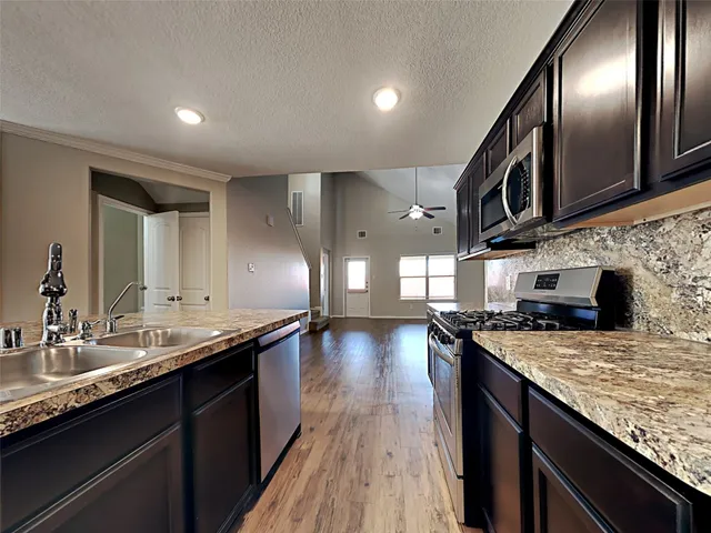 a kitchen with stainless steel appliances granite countertop a sink a stove and a wooden floors