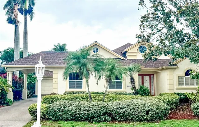 front view of a house with a yard and palm trees