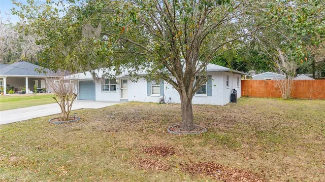 an aerial view of a house with a yard lake and trees all around