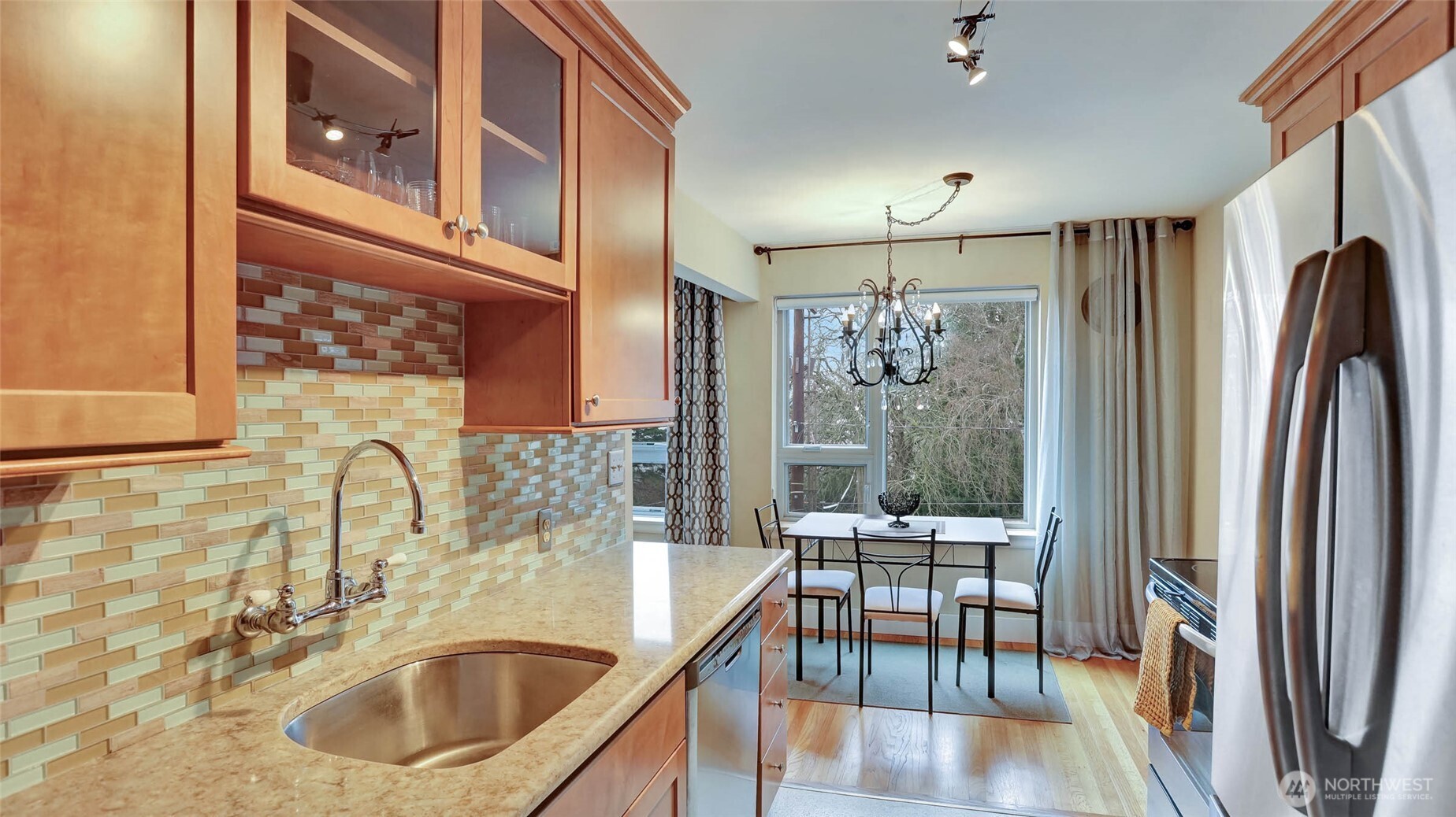 530 West Olympic Place, Unit 304 Seattle, WA 98119 - Photo 11 of 15 a kitchen with stainless steel appliances granite countertop a refrigerator a sink a stove and a dining table with wooden floor