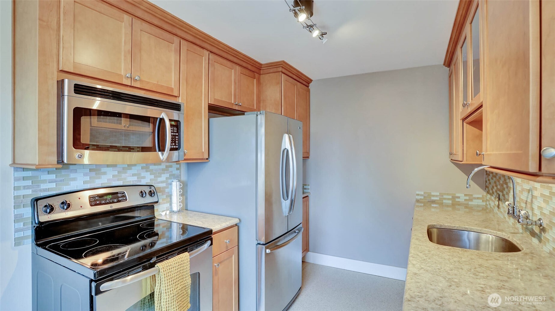 530 West Olympic Place, Unit 304 Seattle, WA 98119 - Photo 9 of 15 a kitchen with granite countertop a refrigerator stove and microwave