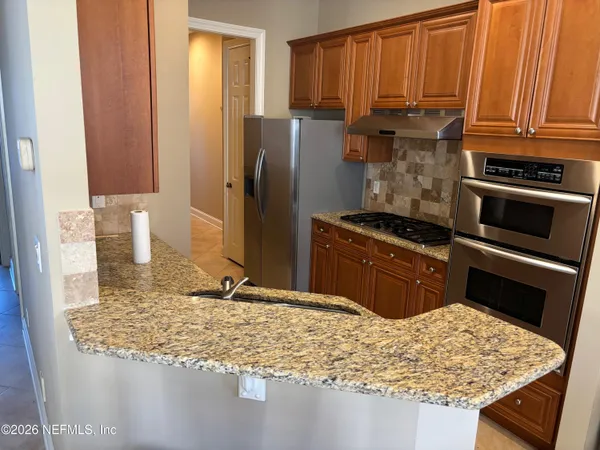 a kitchen with stainless steel appliances granite countertop a refrigerator and a stove top oven