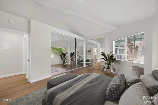 a spacious bedroom with a large window and a wooden floor