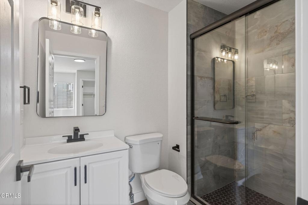 1948 Rory Lane, Unit 5 Simi Valley, CA 93063 - Photo 22 of 25 a bathroom with a toilet a sink a glass door a shower and a mirror