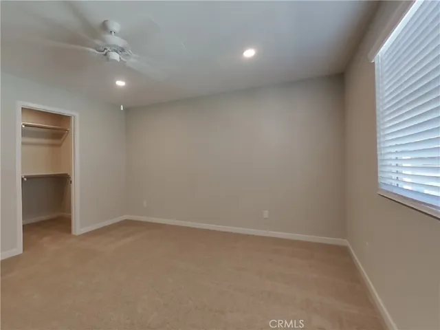 an empty room with a window and a ceiling fan