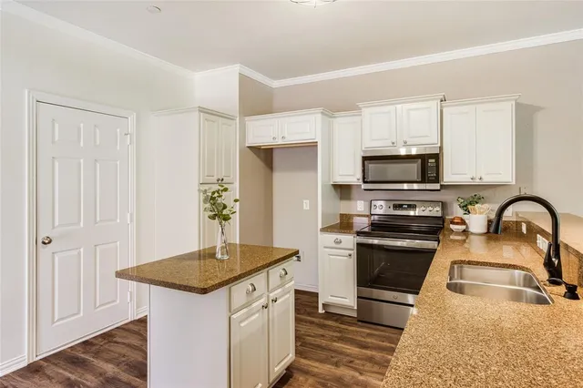 a kitchen with stainless steel appliances granite countertop a stove top oven a sink dishwasher and a refrigerator with wooden floor