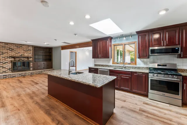 a kitchen with stainless steel appliances granite countertop a stove a sink and a microwave