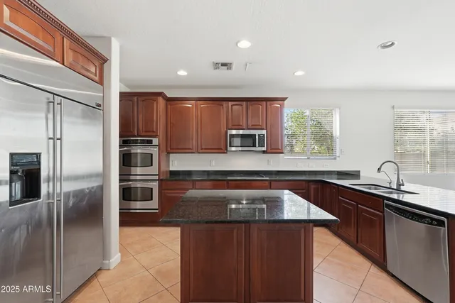a kitchen with kitchen island granite countertop a sink refrigerator and microwave