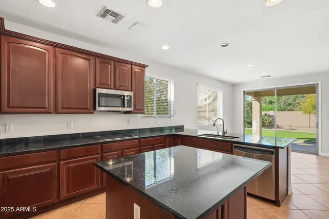 a kitchen with stainless steel appliances granite countertop a sink a microwave cabinets and a dining table