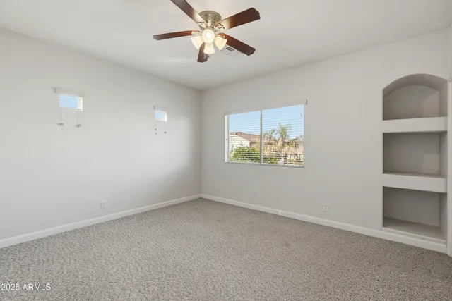 an empty room with windows and fan
