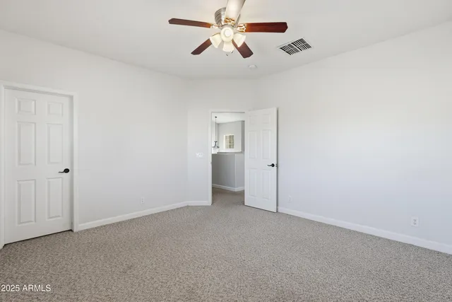 a view of an empty room and chandelier fan
