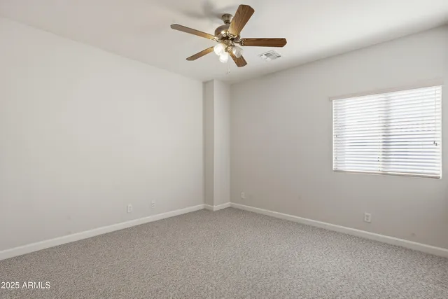 an empty room with a window and a fan