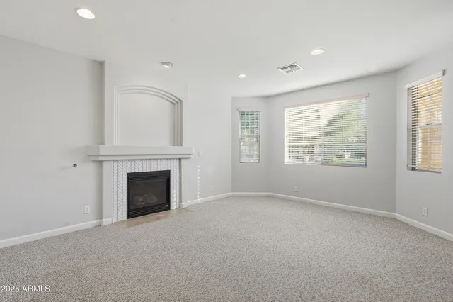 an empty room with windows and fireplace