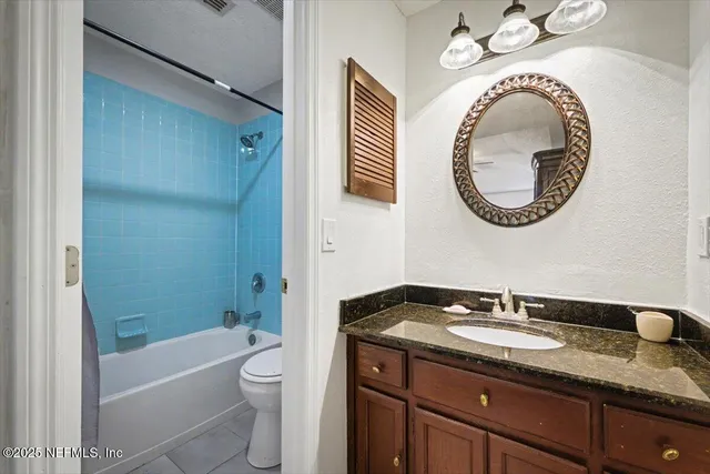a bathroom with a granite countertop toilet sink and mirror