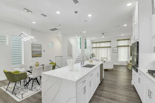 a kitchen with stainless steel appliances granite countertop a stove top oven a sink dishwasher a dining table and chairs with wooden floor