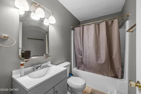 a bathroom with a sink toilet a mirror and shower curtain