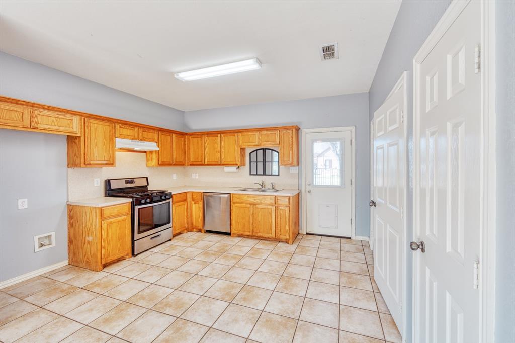 216 East Walcott Street Pilot Point, TX 76258 - Photo 3 of 12 a kitchen with stainless steel appliances granite countertop a stove a sink and a refrigerator