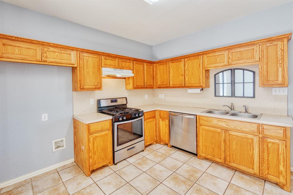 216 East Walcott Street Pilot Point, TX 76258 - Photo 4 of 12 a kitchen with stainless steel appliances granite countertop a stove a sink and a microwave