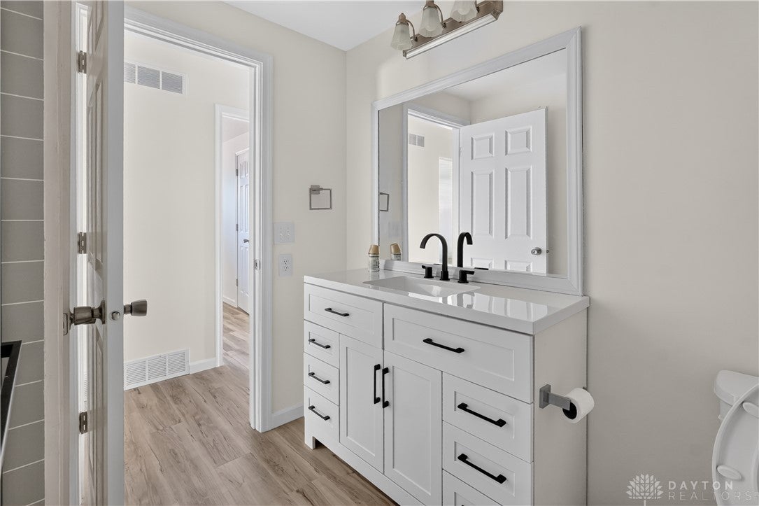 1243 Student Avenue Springfield, OH 45503 - Photo 16 of 38 An updated white vanity stands alongside smooth plank flooring in this clean bathroom.