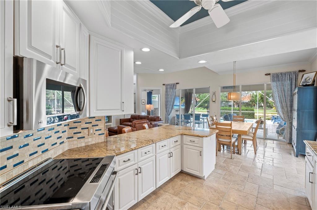 4401 Novato Court Naples, FL 34109 - Photo 16 of 50 a large kitchen with kitchen island granite countertop a sink and white cabinets